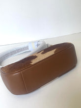Load image into Gallery viewer, A brown leather shoulder bag with a brown and beige cowhide patch on the top flap, resting on a white surface.