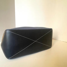 Load image into Gallery viewer, Black leather clutch bag with white stitching on a beige surface