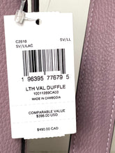 Load image into Gallery viewer, A white retail hangtag attached to a lavender-purple textured leather item, showing printed product information including barcode, model text, and price details.