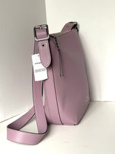 Load image into Gallery viewer, A dusty purple pebbled leather shoulder bag with a matching adjustable strap, silver buckle, and a hanging white Coach brand tag, set against a plain off-white background.