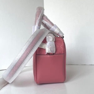 Pink handbag with a decorative strap on a white background