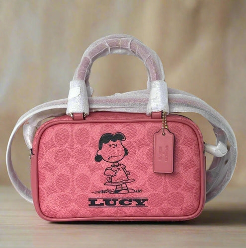 Pink handbag with a character design and 'Lucy' text on a beige background