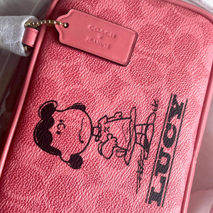 Pink Coach bag with a cartoon design and 'Lucy' text, featuring a gold tag.