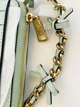 Load image into Gallery viewer, Close-up of a light sage green leather handbag with a gold-tone chain strap and bow details, showing the zipper and hardware.
