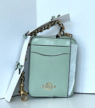 Load image into Gallery viewer, A Coach mini crossbody bag in a pale mint green color, featuring a chain strap, gold-tone hardware, and a white hangtag, set against a white background.