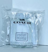 Load image into Gallery viewer, A Coach New York garment inside a clear plastic bag, with the Coach logo printed on the front and a white product tag attached on the left side.