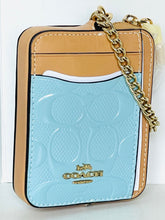 Load image into Gallery viewer, Coach crossbody phone bag in light blue and tan leather with a gold chain strap, shown on a white background.
