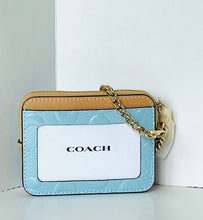 Load image into Gallery viewer, A Coach crossbody card holder bag in light blue textured leather with a tan leather top trim, a gold chain strap, and a white front card slot displaying the Coach logo.