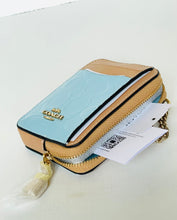 Load image into Gallery viewer, A Coach zippered phone wallet in light blue and tan leather with gold hardware, shown with its hangtag and tassel on a white surface.