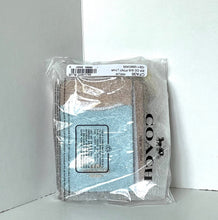 Load image into Gallery viewer, A Coach wallet in clear plastic packaging, featuring a light blue glittery front panel and a brown textured back, set against a white corner background.