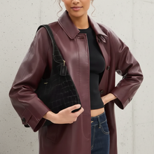 Load image into Gallery viewer, Person wearing a burgundy coat holding a black textured bag against a light gray background