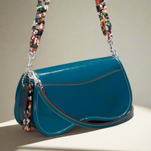 Load image into Gallery viewer, Blue handbag with a colorful strap on a light gray background