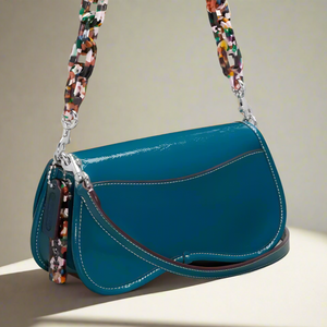 Blue handbag with a colorful strap on a light gray background