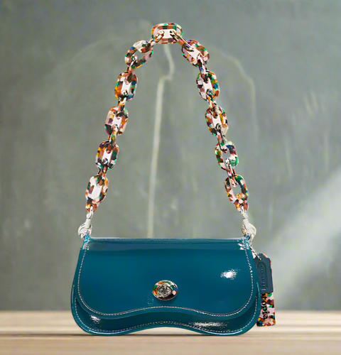 Blue handbag with a colorful chain strap on a light gray background