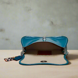 Blue handbag with a strap on a light gray background