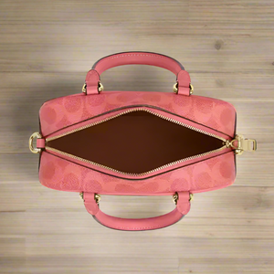 Pink handbag with gold accents on a light gray background