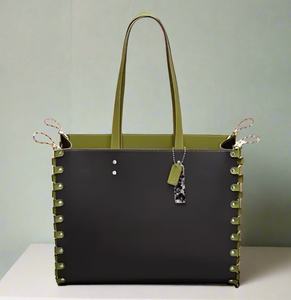 Green and black tote bag with studded details on a light gray background