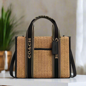 Coach handbag with straw-like texture and black accents on a white background