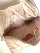 Load image into Gallery viewer, Close-up of the interior of a light beige or cream nylon bag, showing the lining, zipper, and a small brown leather brand patch.