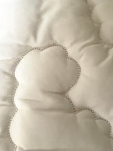 Load image into Gallery viewer, Close-up of a quilted cream-colored pillow or cushion with stitched cloud-like outlines and a fine ribbed fabric texture.