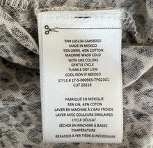 Load image into Gallery viewer, Clothing label with text on a textured fabric background