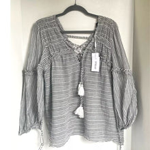 Load image into Gallery viewer, Black and white striped blouse with tassels on a hanger against a white wall