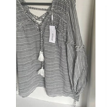 Load image into Gallery viewer, Black and white striped shirt with tassels on a hanger against a white background