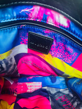 Load image into Gallery viewer, Close-up of the interior of a colorful bag, showing a black leather brand patch that reads 'mimosa Paris' sewn onto a vibrant, patterned blue, pink, and yellow lining.