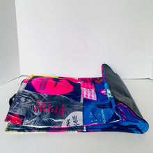 Load image into Gallery viewer, A folded reusable tote bag with a glossy, colorful collage print featuring pink, blue, black, and white graphics, set against a plain white background.