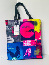 Load image into Gallery viewer, Large tote bag with black handles, featuring a vibrant collage print of pink, blue, yellow, and black graphic panels with text and imagery.