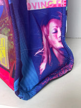 Load image into Gallery viewer, A close-up of a padded fabric item, likely a cushion or bag, featuring a blue and purple graphic print with a stylized face and partial text on a light background.