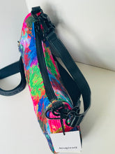 Load image into Gallery viewer, A colorful crossbody bag with a vibrant abstract paint-splatter pattern in pink, blue, green, and yellow, featuring black straps and hardware, with a Desigual brand tag visible.