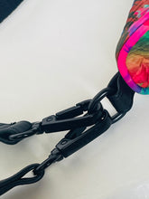 Load image into Gallery viewer, Close-up of a colorful tie-dye fabric strap or bag detail connected to black metal hardware and a black strap on a plain light background.