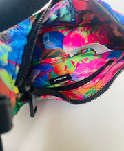 Load image into Gallery viewer, Close-up of the colorful interior of a fanny pack or waist bag, showing a bright floral print with blue, pink, green, and orange tones, black zippers, and a small visible 'Despatch' brand tag.
