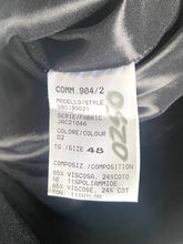 Load image into Gallery viewer, A close-up of a white garment care label sewn inside a black satin or silk-like garment lining. The label reads 'COMM.