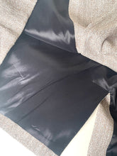 Load image into Gallery viewer, Close-up of a garment interior showing a black satin lining and a textured beige fabric exterior.