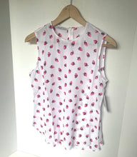Load image into Gallery viewer, White sleeveless top with pink strawberry pattern on a wooden hanger against a white background