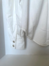Load image into Gallery viewer, Close-up of a white shirt with buttons on a light background
