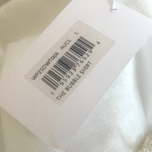 Load image into Gallery viewer, Close-up of a clothing tag with a barcode and text on a white fabric background
