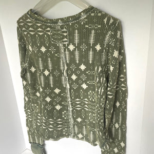 Green patterned sweater on a hanger against a white background