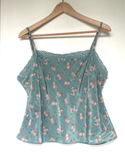 Load image into Gallery viewer, A light blue satin camisole top with a pink floral print, featuring lace trim along the neckline and thin spaghetti straps, hanging on a wooden hanger against a plain white wall.