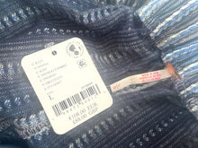 Load image into Gallery viewer, Close-up of a clothing tag on a textured fabric background