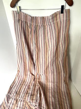 Load image into Gallery viewer, Striped pants hanging on a hanger against a white wall