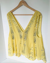 Load image into Gallery viewer, A yellow sleeveless V-neck top with silver rhinestone geometric patterns, hanging on a wooden hanger against a white wall.