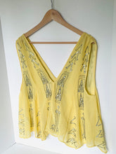 Load image into Gallery viewer, A yellow sleeveless V-neck top with silver rhinestone geometric patterns, hanging on a wooden hanger against a white wall.
