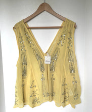 Load image into Gallery viewer, A pale yellow sleeveless sheer top with silver rhinestone geometric patterns, hanging on a wooden hanger against a white wall.