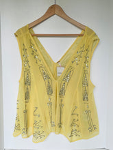 Load image into Gallery viewer, A yellow sleeveless V-neck top with silver rhinestone embroidery, hanging on a wooden hanger against a white wall.