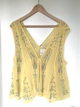 Load image into Gallery viewer, A pale yellow sleeveless top with silver rhinestone embroidery, hanging on a wooden hanger against a white wall.