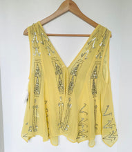 Load image into Gallery viewer, A yellow sleeveless V-neck top with silver rhinestone embellishments, hanging on a wooden hanger against a plain white wall.