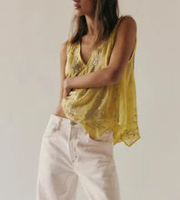 Load image into Gallery viewer, A woman wearing a yellow sleeveless embroidered top and white jeans, photographed against a plain light background.